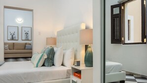 A modern bedroom with a large bed, a nightstand, a lamp, and a wall-mounted mirror. - Aqua Suite | 1 BR Apt at Old San Juan (San Juan)