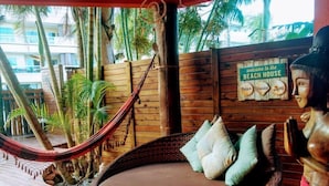 A hammock chair with cushions, a wooden wall with a 'Welcome to the Beach House' sign, and a statue of a woman.