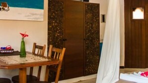 A bedroom with a bed, a TV, a dining table with chairs, and a decorative painting.