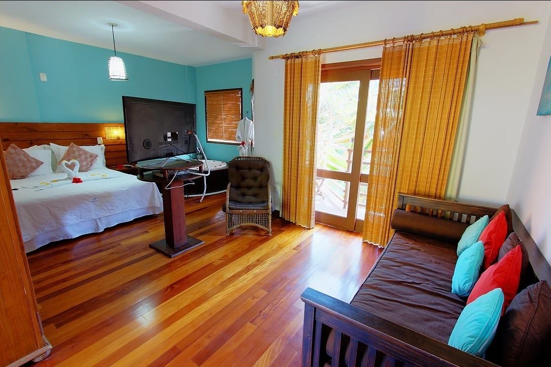 A room with a bed, a sofa, a chair, a desk, and a TV.