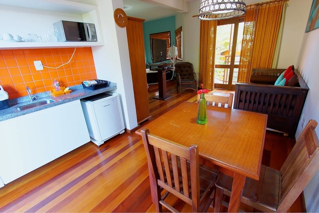 A kitchen with a microwave, a sink, and a dining area with a table and chairs.