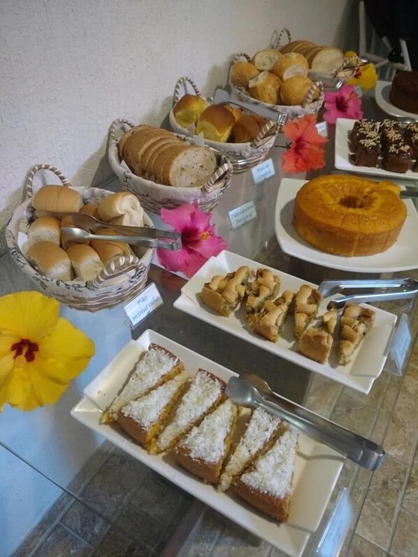 Un bufé con diversas opciones de panadería, incluyendo pan, pasteles y un pastel.
