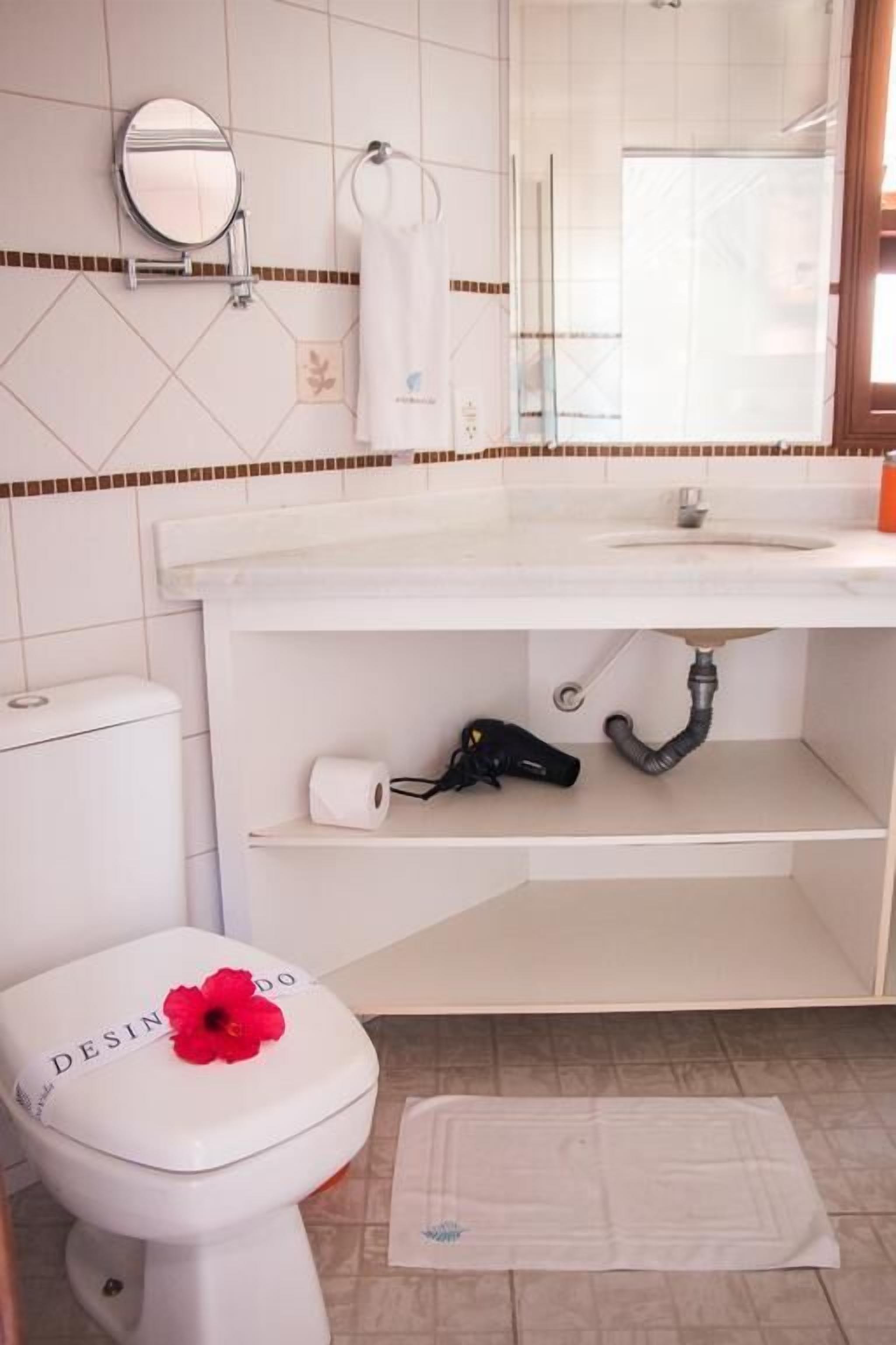 Ein Badezimmer mit Toilette, Waschbecken, Spiegel und Duschbereich.