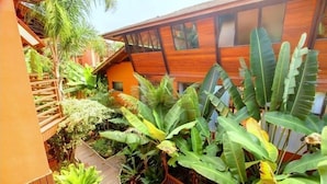 A modern building with a wooden facade, surrounded by lush tropical plants and a wooden deck.