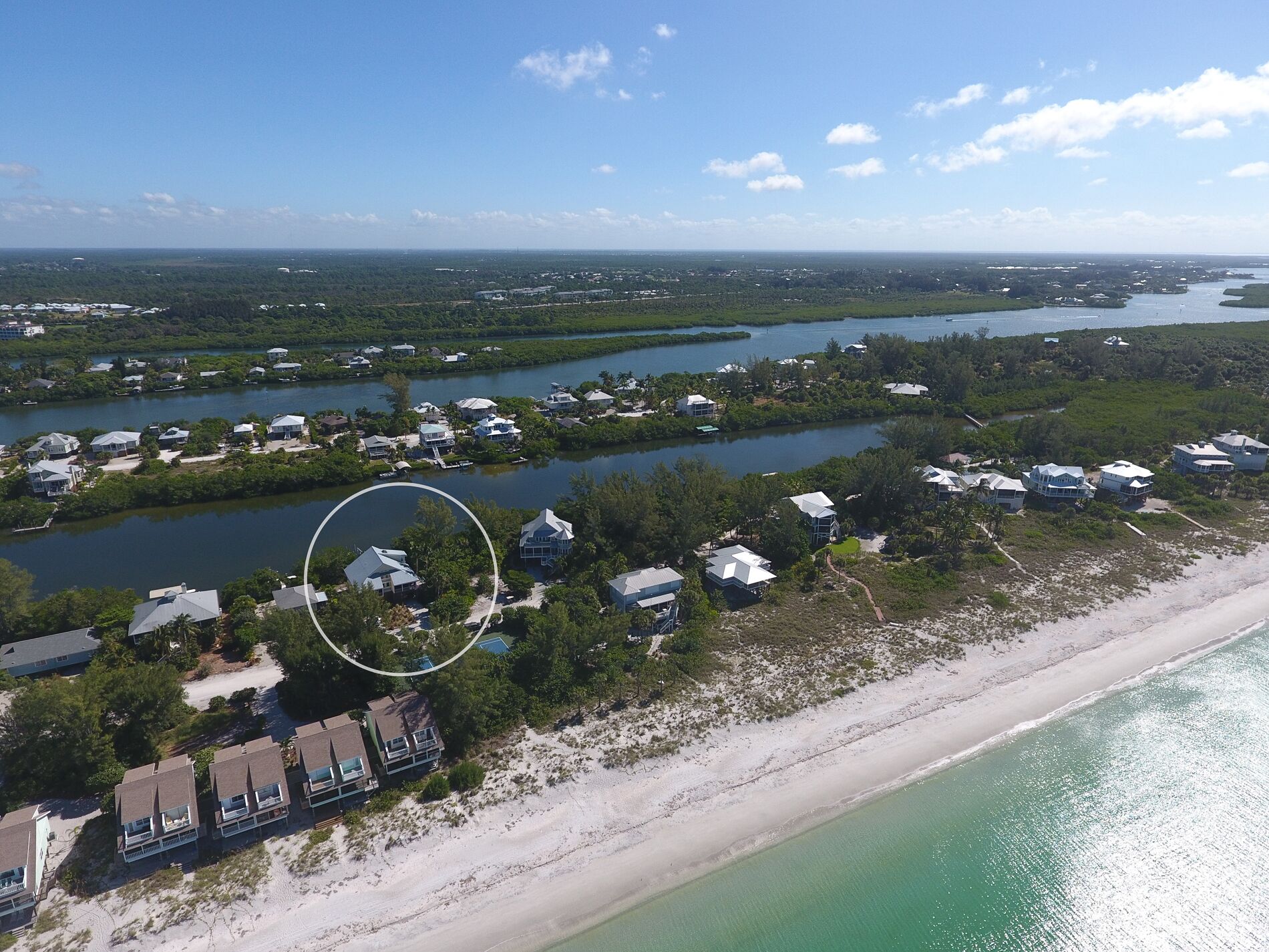 An aerial view of a coastal residential area with houses along the shoreline and a bay.