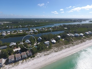 Vista aérea de uma área residencial costeira com casas ao longo da linha de costa e uma baía.