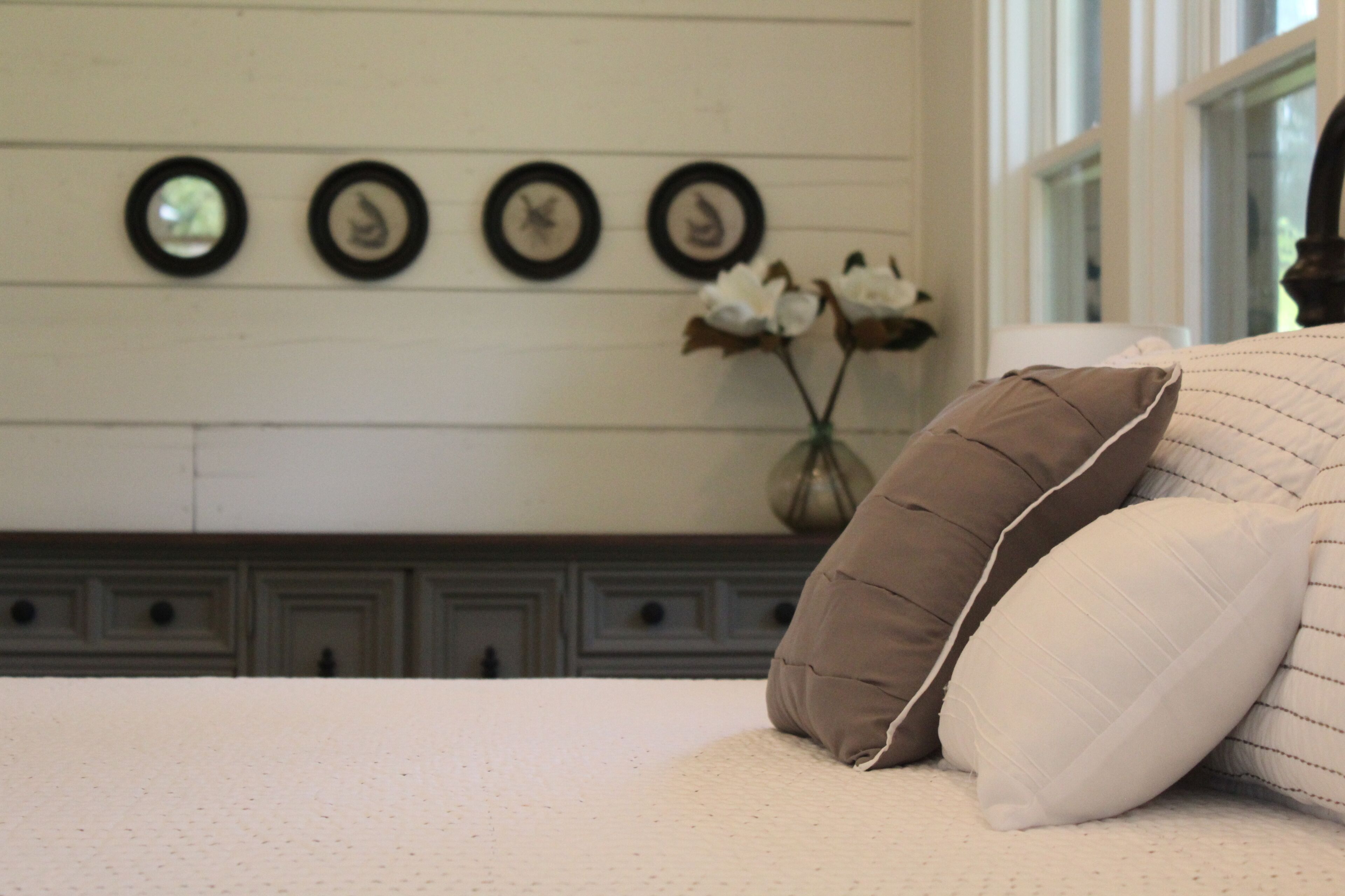 A bed with pillows, a vase with flowers, and wall-mounted clocks.