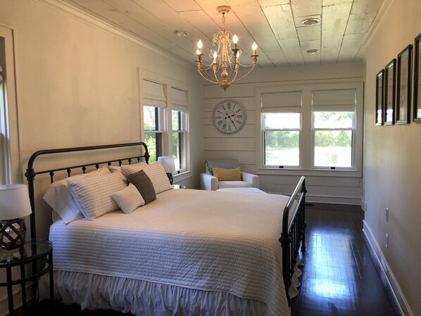 A bedroom with a bed, a chandelier, a clock, and windows. - AS SEEN ON FIXER UPPER "THE BRICK HOUSE" (Waco)
