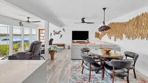 Una sala de estar moderna con comedor, ventanas amplias y vistas al exterior.