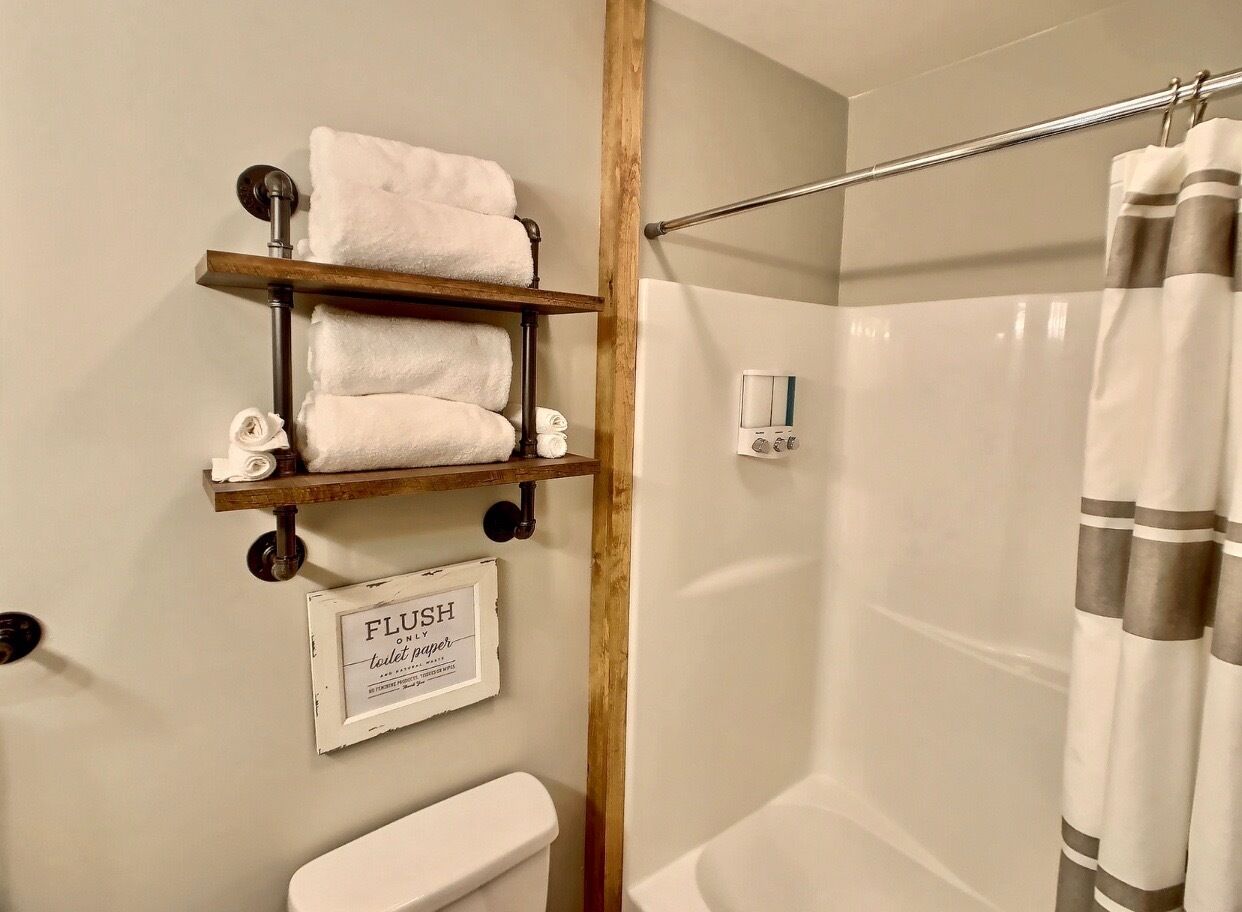 Une salle de bain équipée de toilettes, d’une douche et d’un porte-serviettes avec des serviettes pliées.