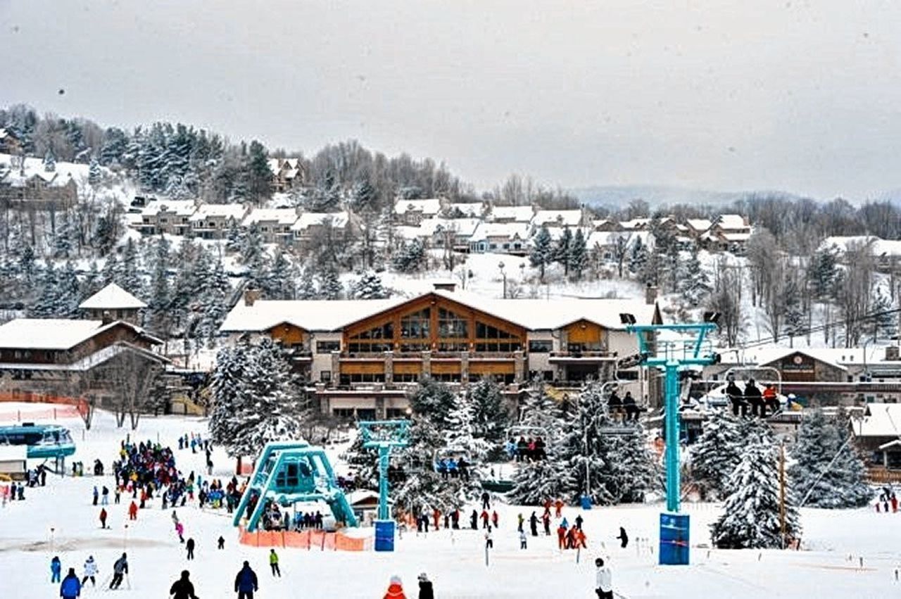 Une station de ski dotée d’un grand chalet, de remontées mécaniques et offrant un paysage enneigé.