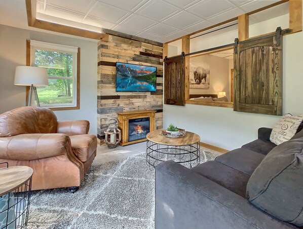 Ein gemütliches Wohnzimmer mit Kamin, Ledersofas, einem Couchtisch und einem Wand-Fernseher.