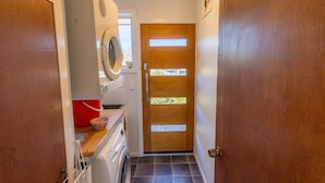 A laundry room with a washing machine, dryer, and a wooden door with a window. - Rejuvenate on Rata · Rejuvenate on Rata, Twizel FREE WIFI (Twizel)