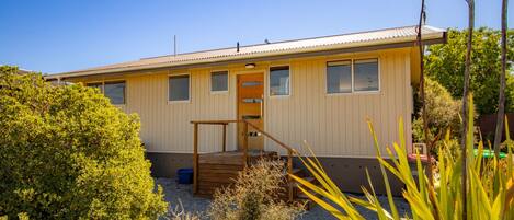 A single-story house with a front porch, a small deck, and a gravel driveway.
