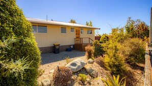 A single-story mobile home with a front porch, a small garden area with rocks and plants, and a clear blue sky. - Rejuvenate on Rata · Rejuvenate on Rata, Twizel FREE WIFI (Twizel)