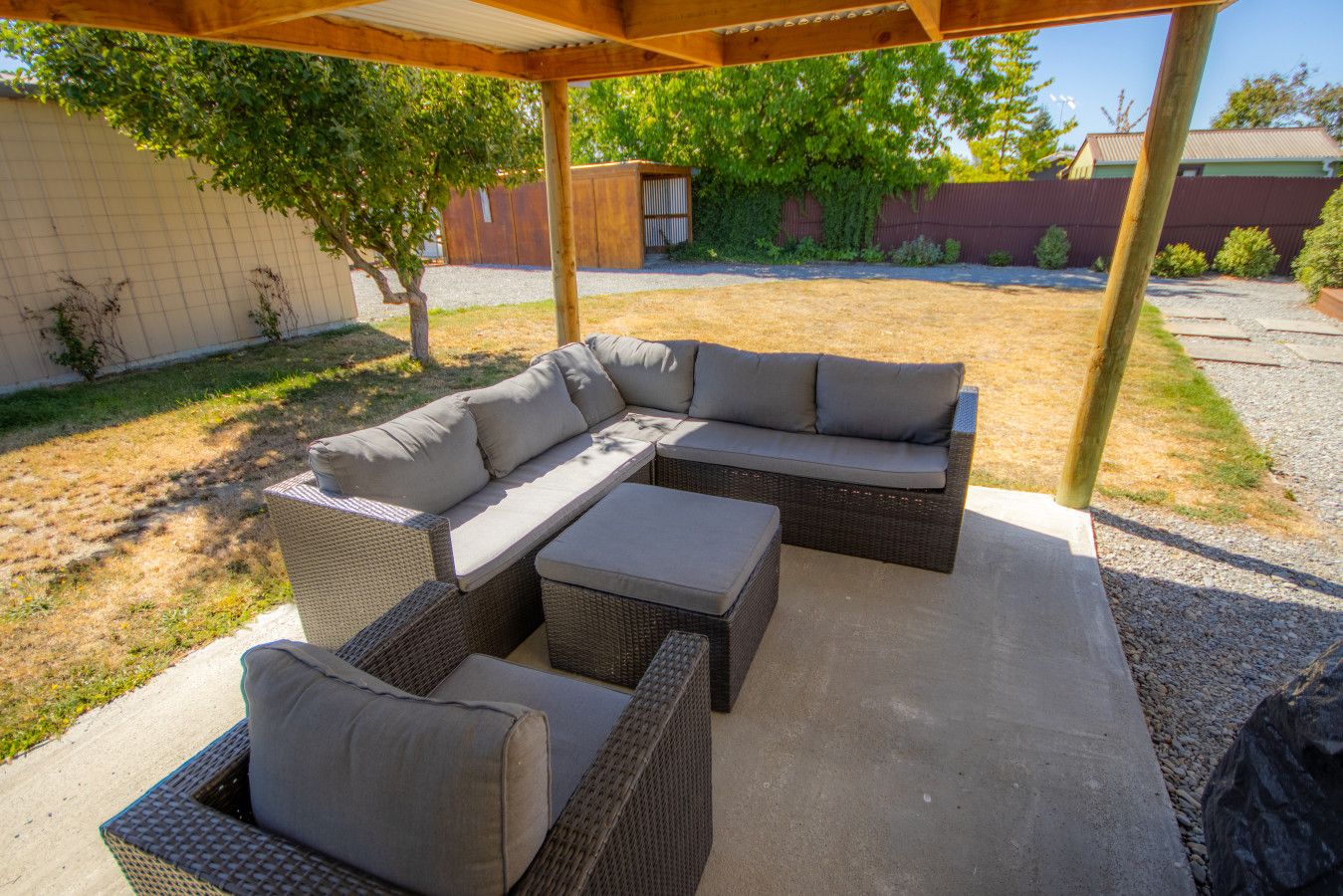 An outdoor patio with a sectional sofa and two armchairs.