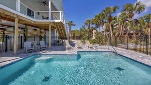 A pool area with lounge chairs and a staircase leading to a second floor. - Family Tides: Beach Pool and Dock..This 5 Bedroom beach house has it all! (Placida)
