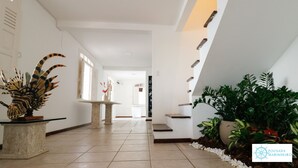 A modern hotel corridor with a tiled floor, a central column, and a staircase. - Pousada Marinheiro (Cairu)