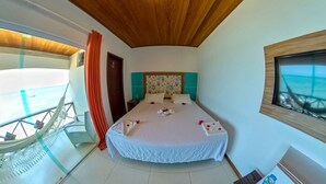 A bedroom with a bed, a window with a view, a wooden ceiling, and a balcony with a railing. - Pousada Marinheiro (Cairu)