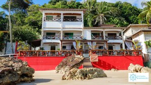 A multi-story building with balconies, surrounded by rocks and greenery. - Pousada Marinheiro (Cairu)