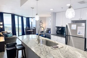 A modern kitchen with a marble countertop, stainless steel appliances, and a view of the ocean. - Beachfront Condo in Panama City Beach with Sunset Views • Pools • Beach Service (Panama City Beach)