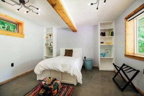 Ein Schlafzimmer mit einem Bett, Einbauschränken, einem Fenster und einer Deckenleuchte.