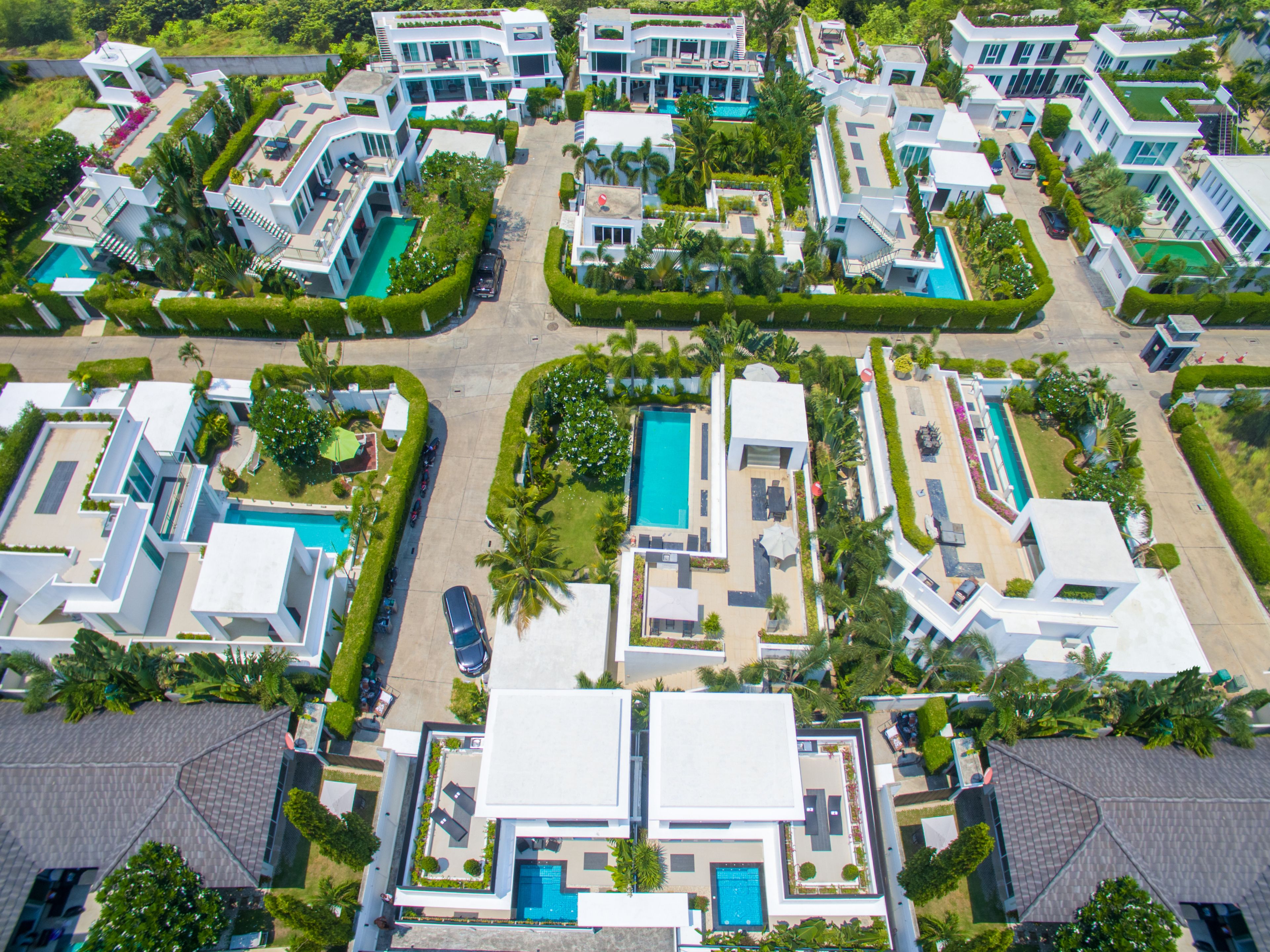 Ein Luftbild eines modernen Wohnkomplexes mit mehreren Schwimmbecken, üppiger Bepflanzung und zeitgenössischer Architektur.