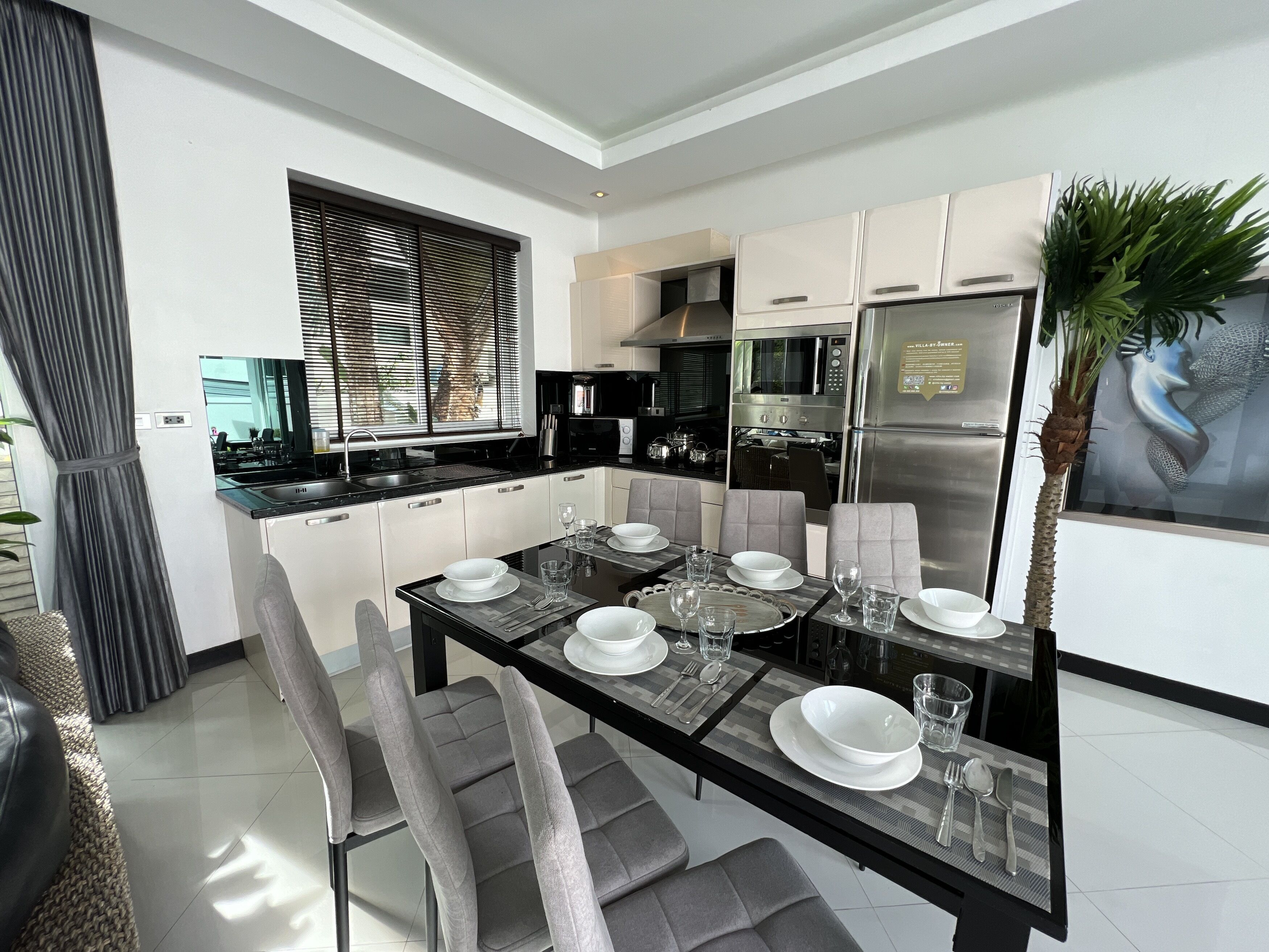 A modern kitchen with a dining area. It includes a kitchen island with seating, a refrigerator, and a microwave.