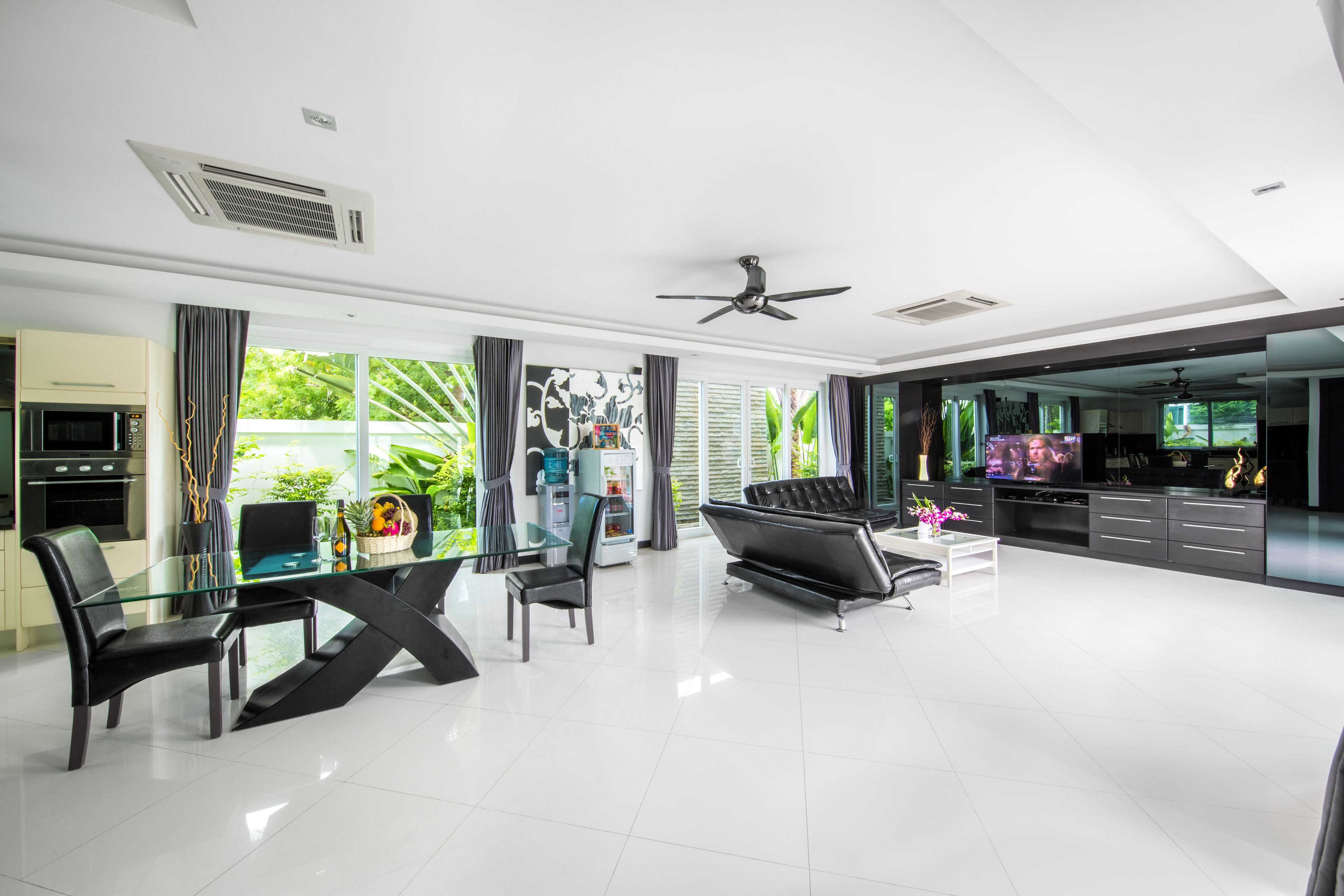 A modern kitchen with a black countertop, a glass dining table, and a black sofa.