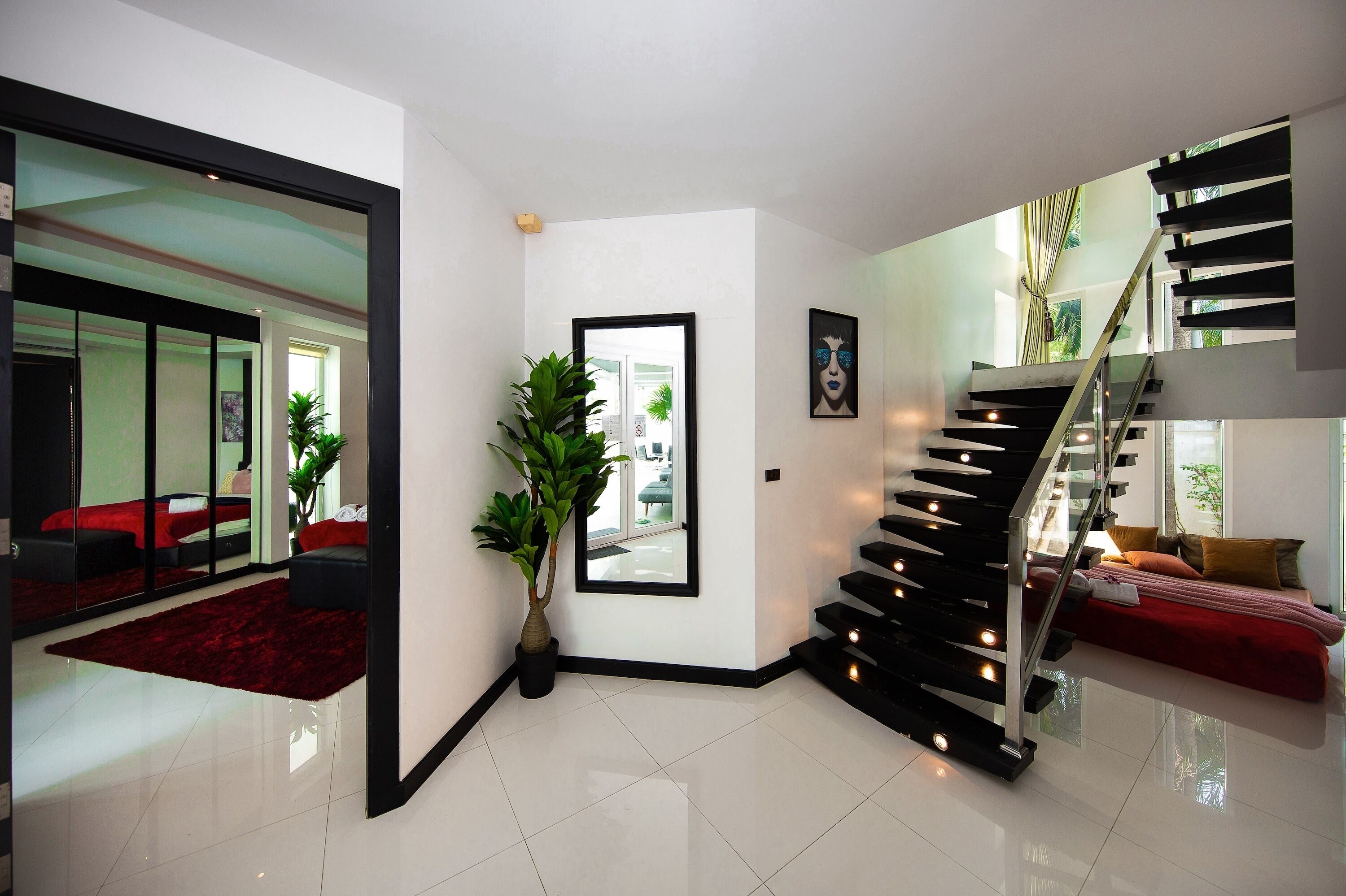 Ein modernes Interieur mit einer Treppe, einem roten Sofa und einer Topfpflanze.