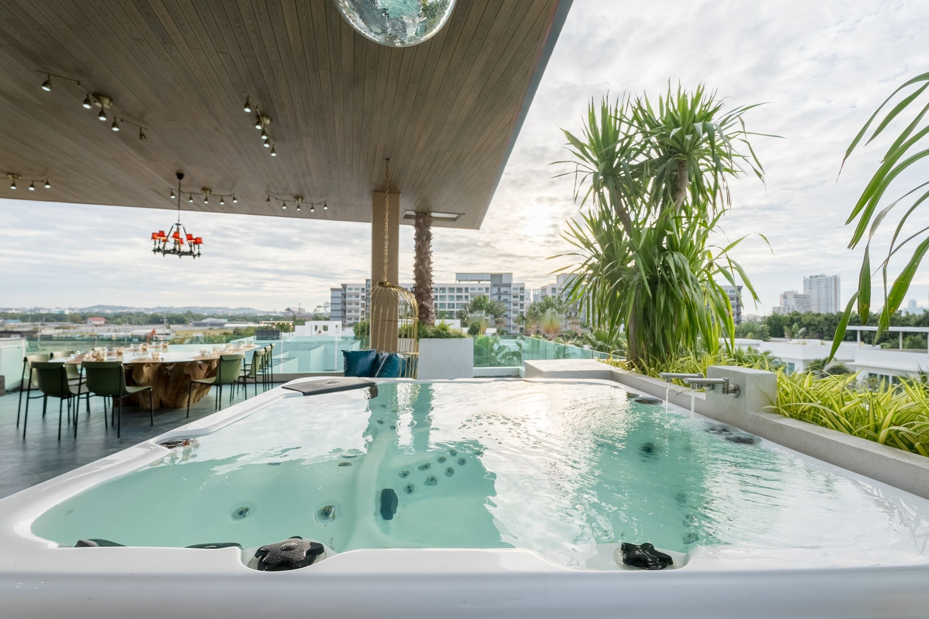 Piscina en la azotea con vistas al horizonte de la ciudad, rodeada de palmeras y una zona de comedor.