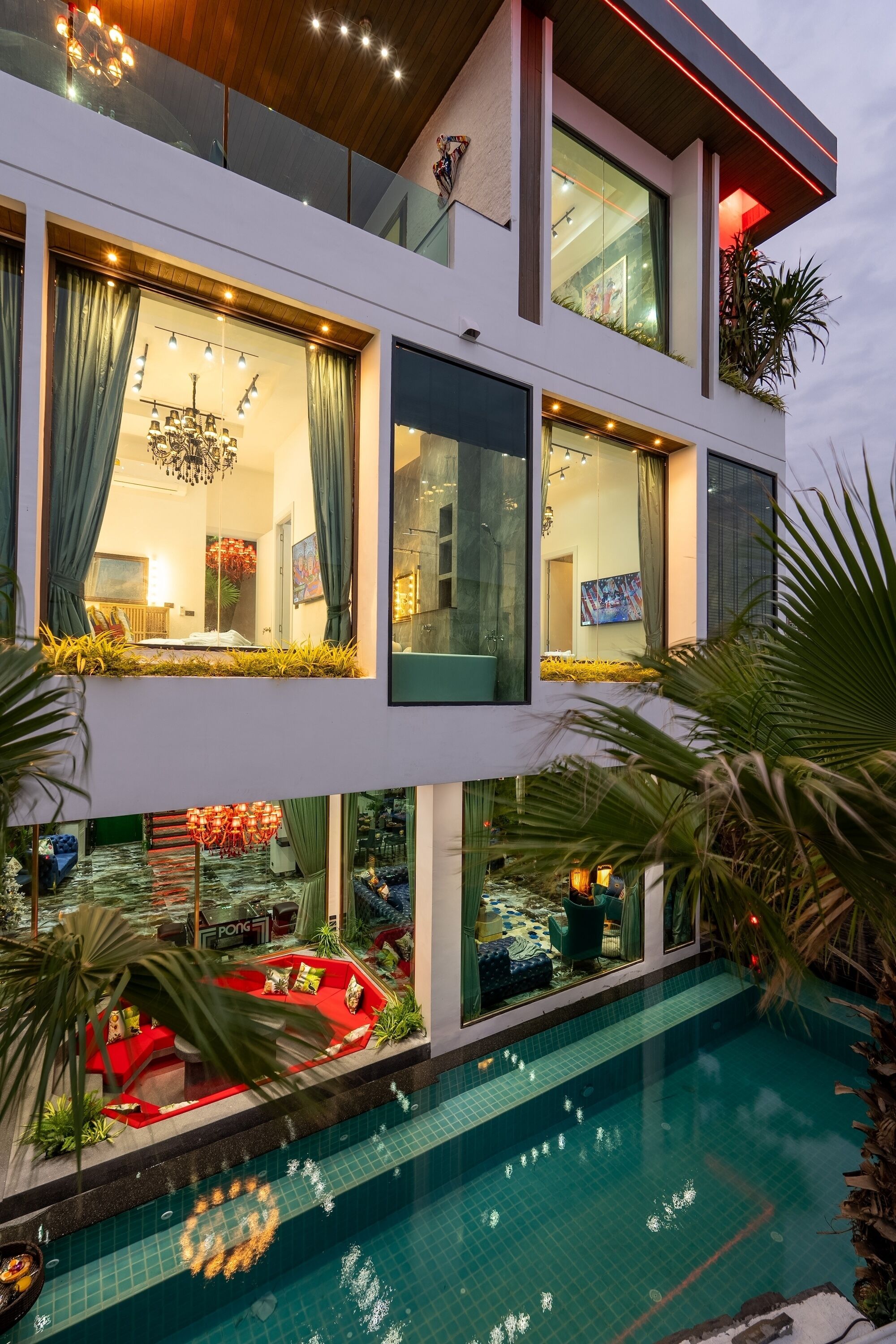 A modern multi-story building with a swimming pool, large windows, and indoor plants.