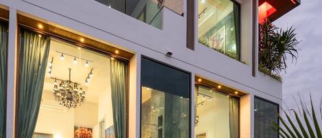 A modern multi-story building with a swimming pool, large windows, and indoor plants.