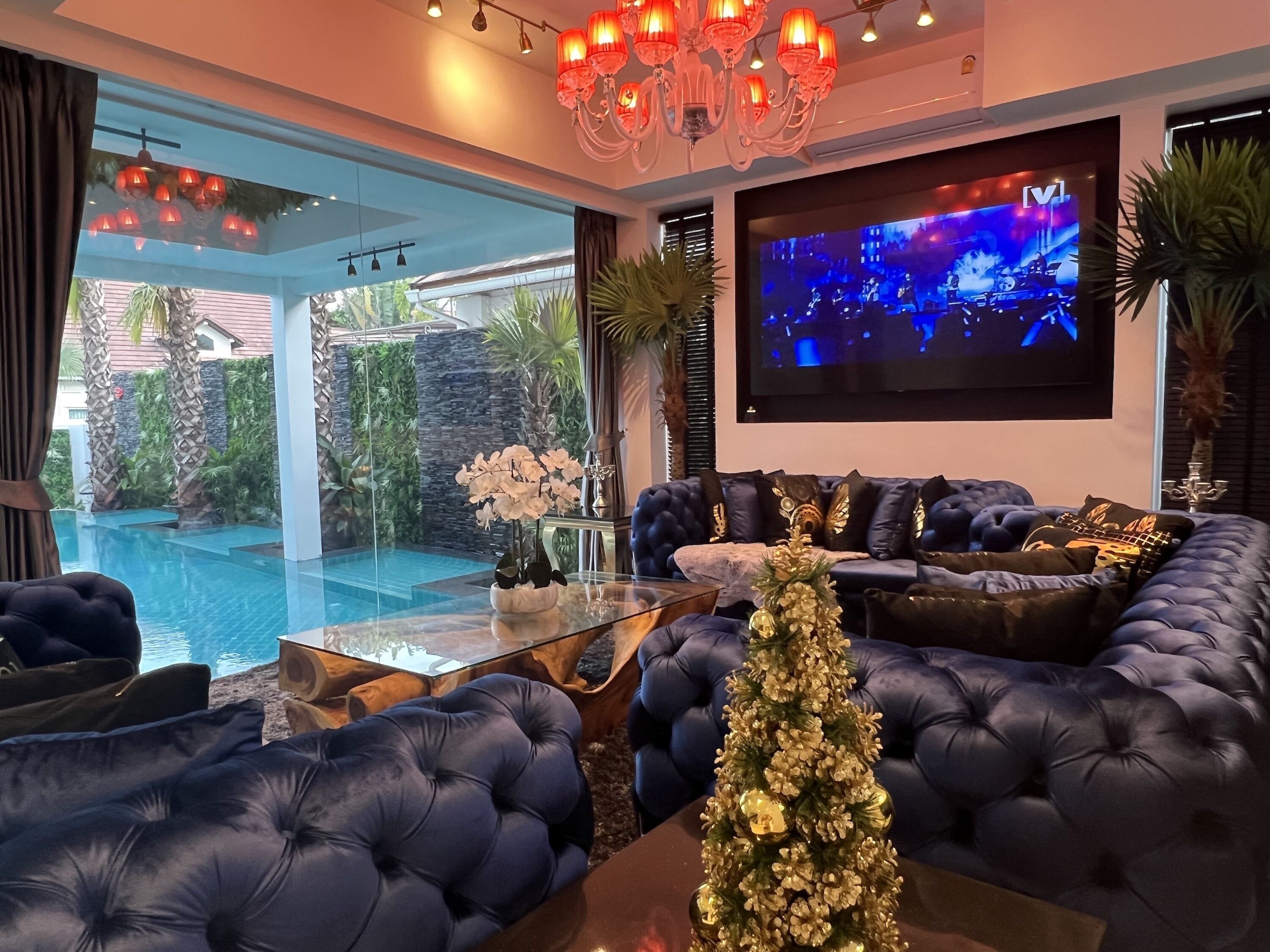 Un salon luxueux avec un grand canapé d’angle, une table basse en verre et un téléviseur fixé au mur.