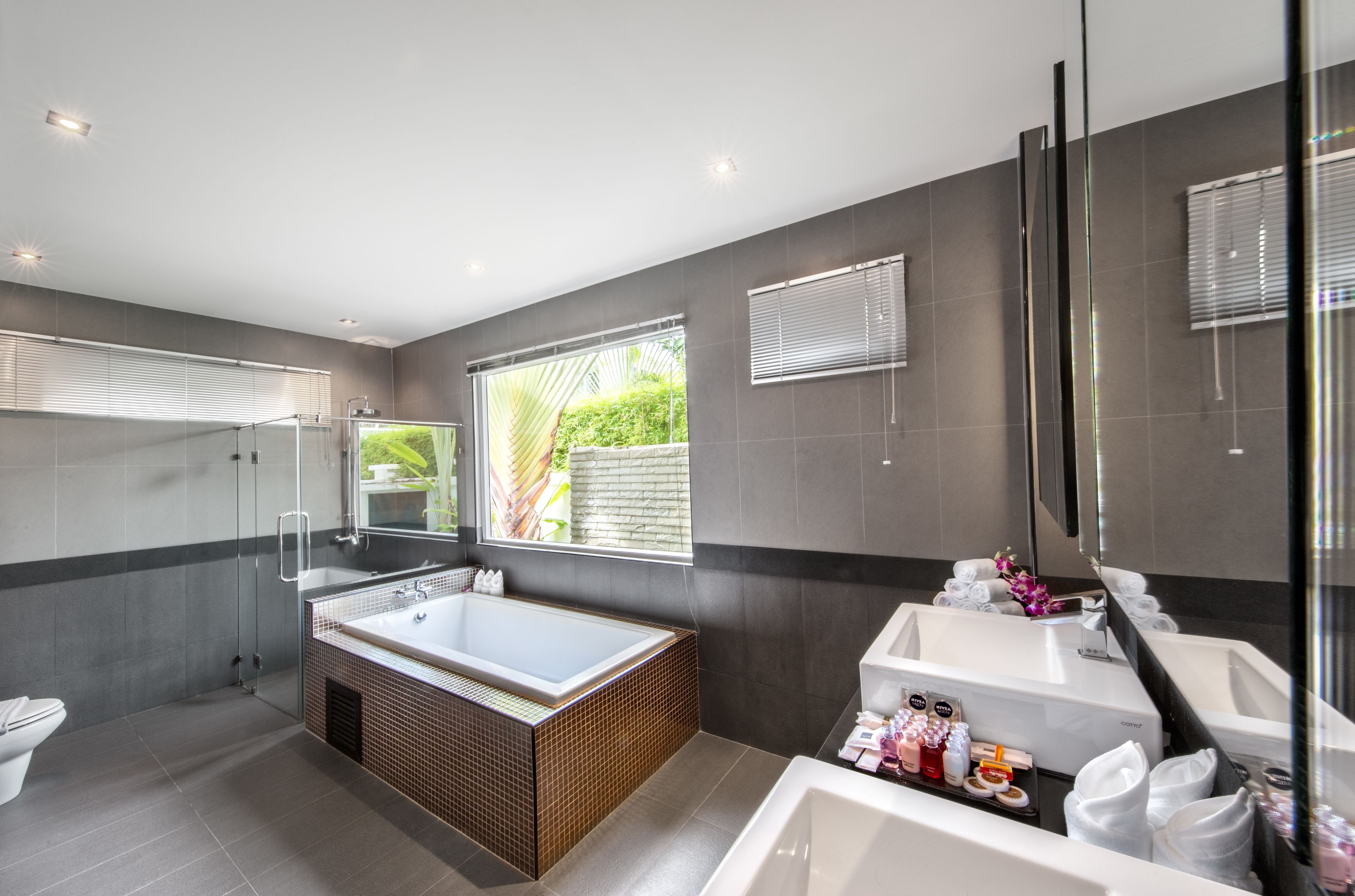 A modern bathroom with a large bathtub, a separate shower area, and a vanity with a mirror.