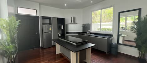 Una cocina moderna con encimera negra, electrodomésticos de acero inoxidable y ventilador de techo.