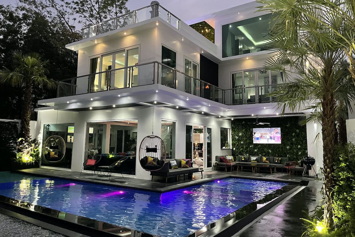 Une maison moderne à deux étages, dotée d’une piscine, de grandes fenêtres et d’un balcon.
