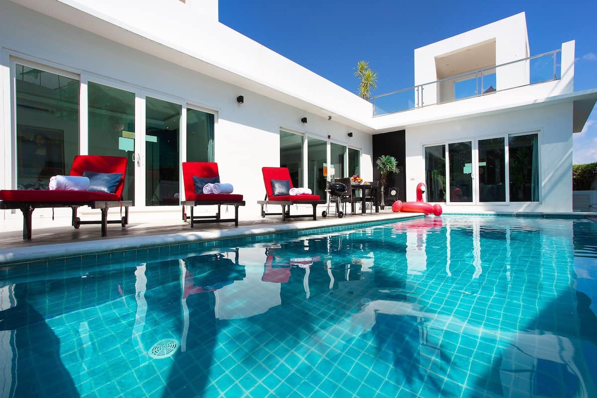 Un espace piscine moderne avec des chaises longues rouges et une piscine à l’eau d’un bleu limpide.