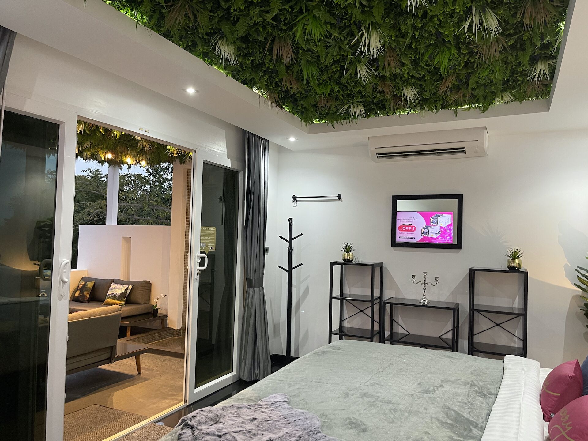 A modern bedroom with a bed, a TV, and a balcony with a sofa.
