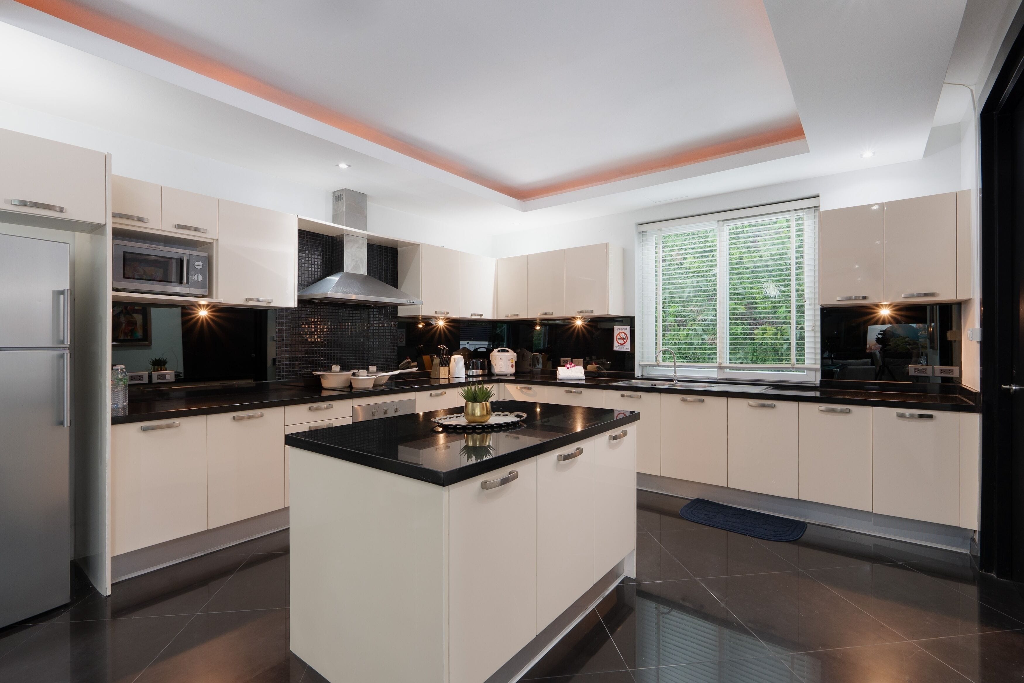 A modern kitchen with a central island, built-in appliances, and a large window providing natural light.
