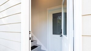 A white front door with a mesh window, a set of stairs leading to a landing, and a white exterior wall. - Jewel in the Sky:   Modern, Private,  Luxurious Loft + EV Charger! (Portland)