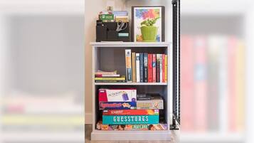 Guests can enjoy a selection of books, games, and a green plant on this bookshelf.