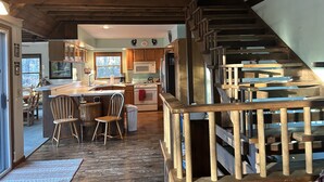 Eine geräumige Küche mit Holzausbau, einer großen Kochinsel und einer Treppe mit Holzwertkante.