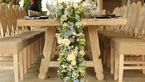 A wooden table with a floral centerpiece, surrounded by wooden chairs. - El Laurel Hotel Boutique (Xochitepec)