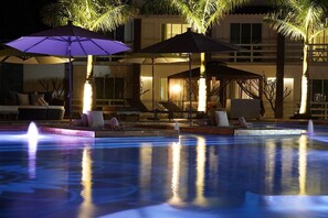 Una piscina al aire libre, sombrillas, sillones reclinables de piscina