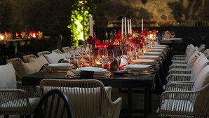 A long dining table set with candles, glasses, and plates, surrounded by wicker chairs. - El Laurel Hotel Boutique (Xochitepec)