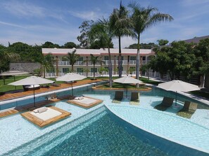 Una piscina con zonas de descanso y palmeras.