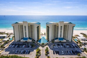 A symmetrical hotel complex with a central pool, parking, and beachfront views. - Sunbird 210w-Cozy Beachfront Condo with Sunset Views – Prime PCB Location (Panama City Beach)