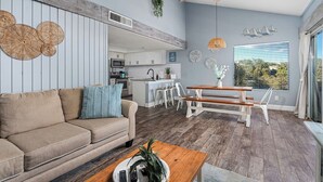 A modern living room with a sofa, coffee table, and dining area. - Cozy Waterfront/Amazing Views/"Paradise Point" in Point Venture! (Leander)