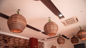 Een modern interieur met geweven hanglampen, een stenen muur en een flatscreen televisie aan de wand.